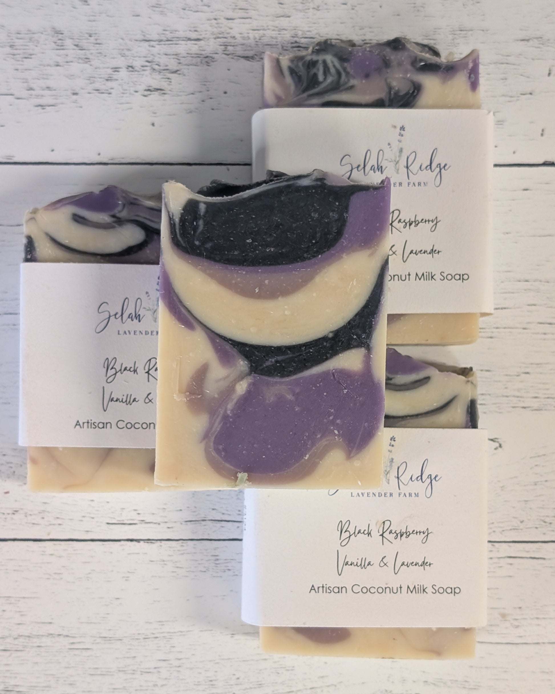 Artisan coconut milk soap with black raspberry, vanilla, and lavender fragrance on a wooden surface.