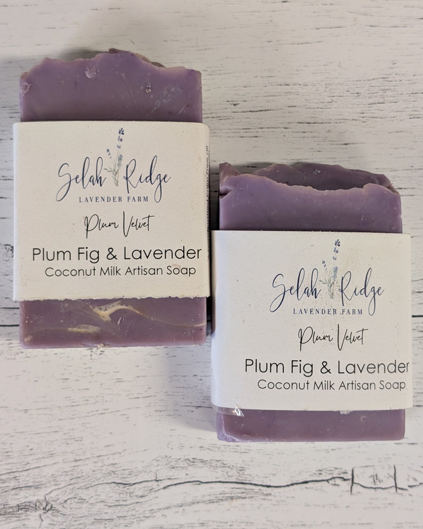 Two bars of Plum Fig & Lavender coconut milk artisan soap with labels on a wooden surface.