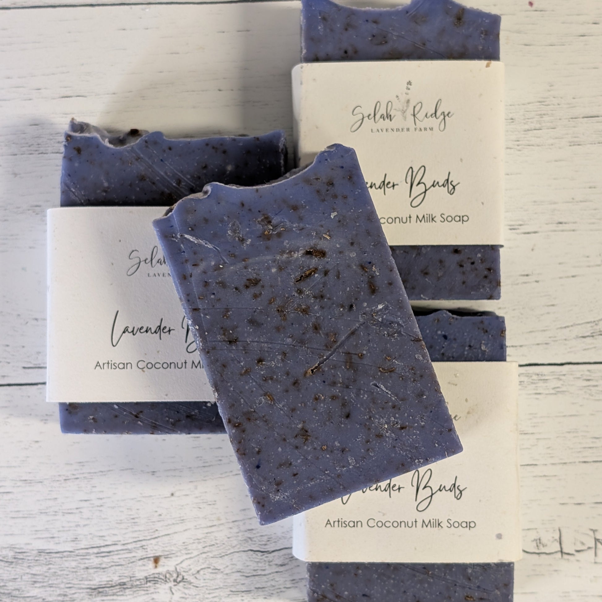 Three bars of lavender soap with labels on a wooden surface