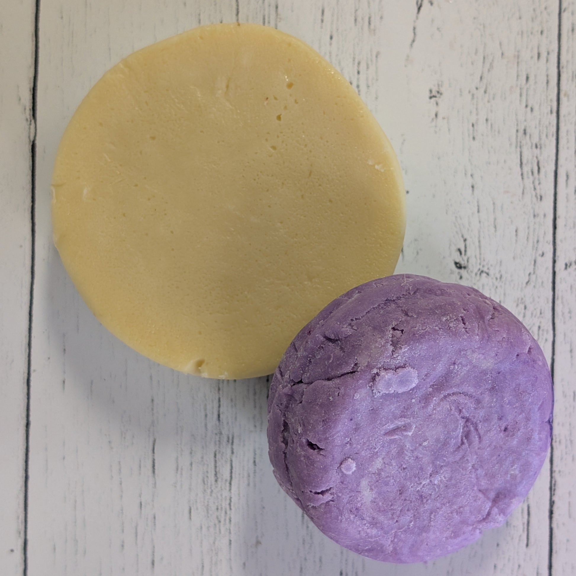 purple lavender shampoo bar and golden conditioner bar on wooden surface