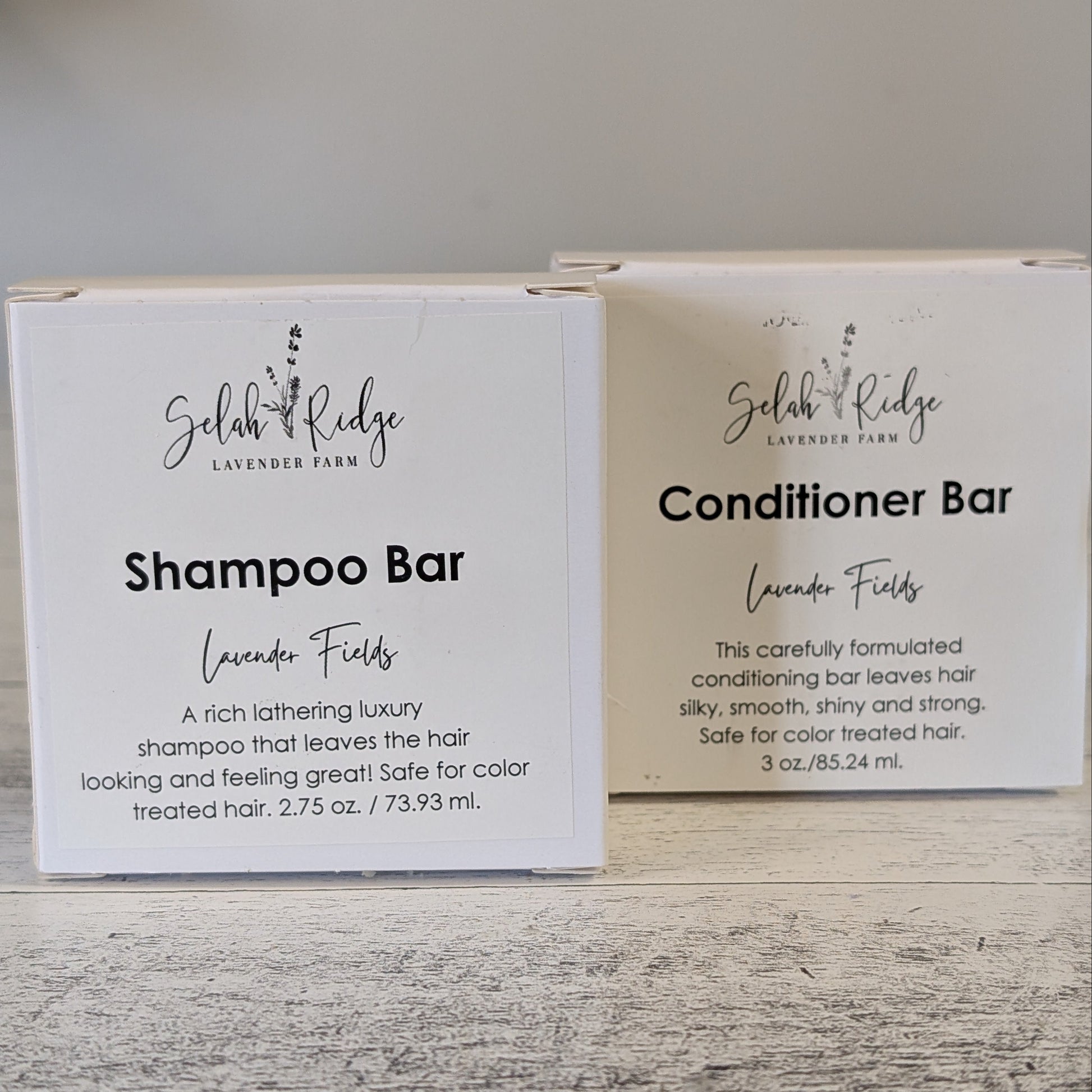 Two boxes of Shampoo Bar and Conditioner Bar from Selah & Ridge on a wooden surface.