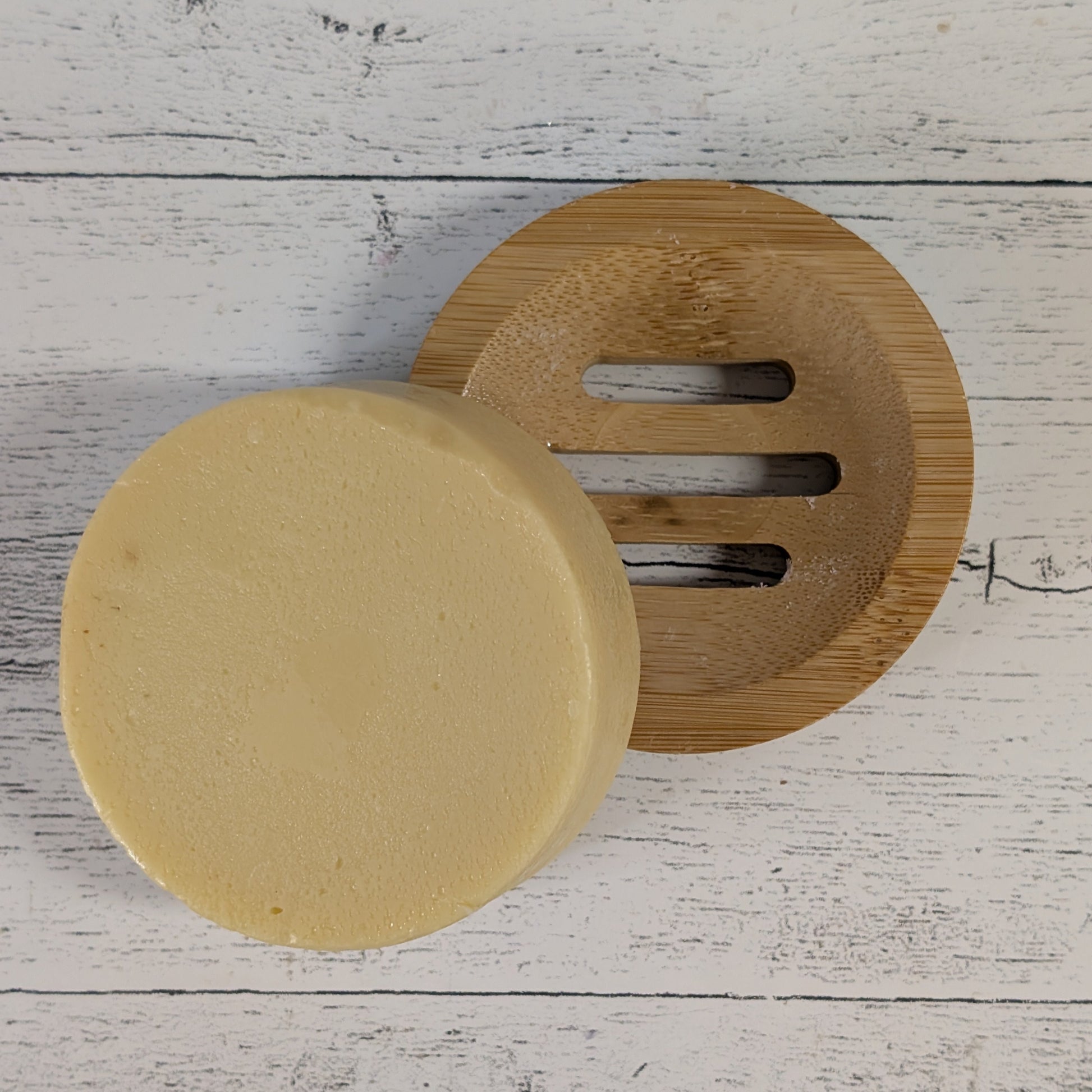 Round beige conditioner bar with a wooden lid on a light wooden surface