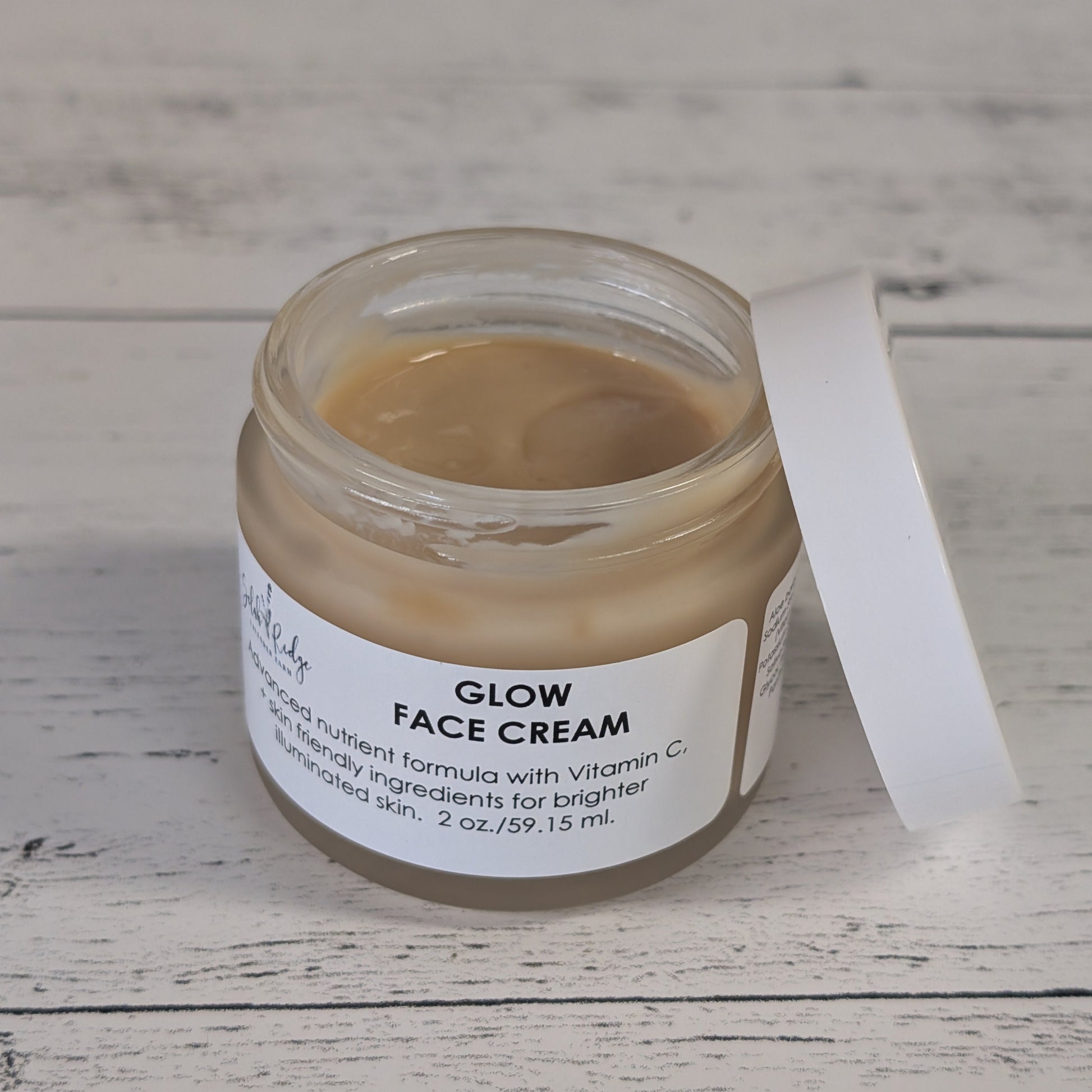 Jar of Glow Face Cream on a wooden surface